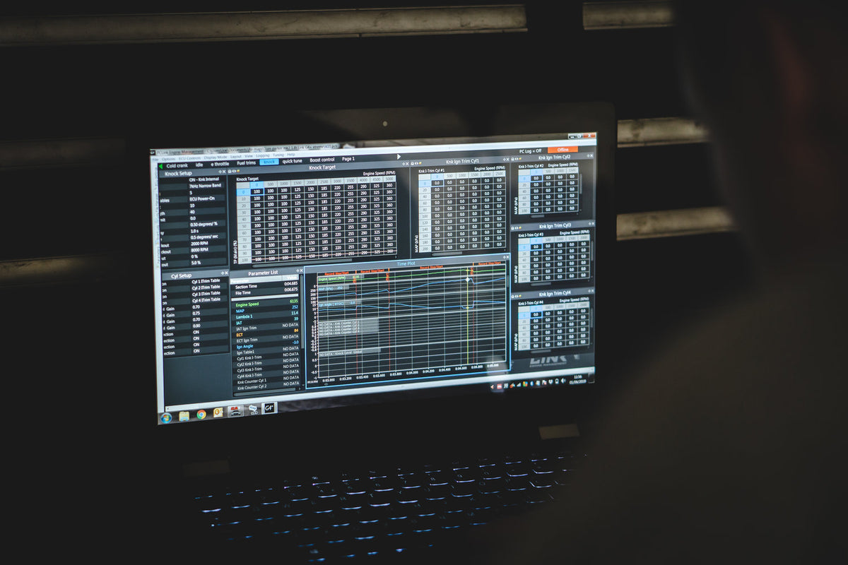 Laptop displaying ECU calibration tables and logged engine data